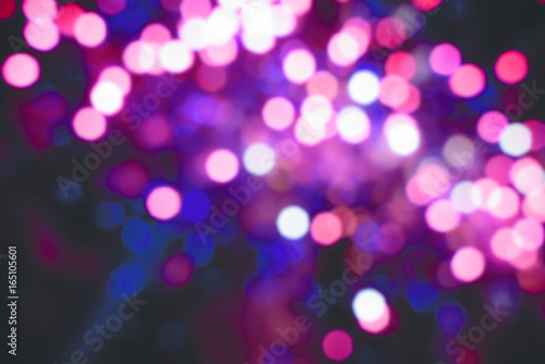 Abstract pink purple colored out of focus blurry party lights in the background at night.