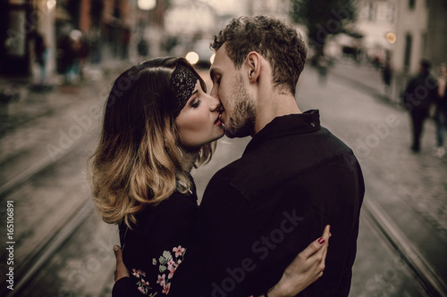 stylish gypsy couple in love kissing hugging in evening city street. woman and man gently embracing, romantic french atmospheric moment. love mood. gypsy wedding. © sonyachny