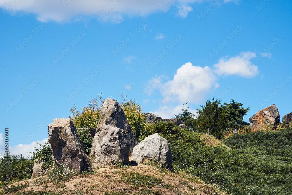 Beautiful landscape with large stones, hills, flowers, cumulus clouds, blue sky on a sunny summer day. National Botanical Garden (Kiev, Ukraine)
