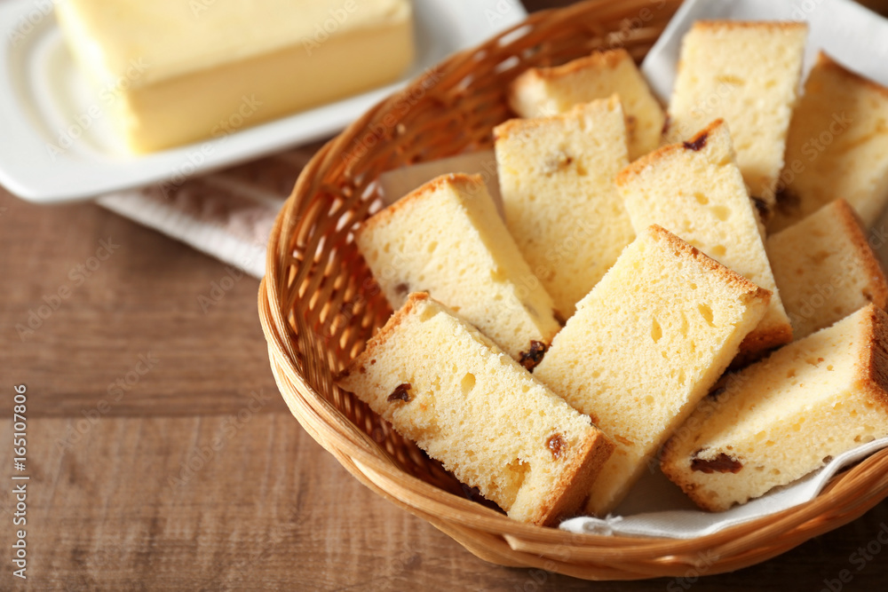 Wicker basket with delicious sliced butter cake on wooden table