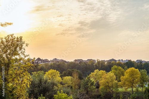 Evening sunset over the roofs of suburban houses. Autumn landscape in backlight sunlight. Belgorod Region, Russia.