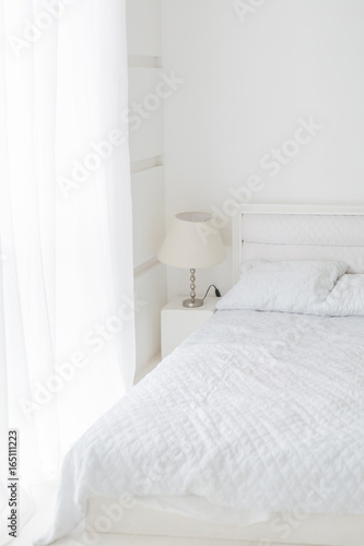 Abstract white room interior with white bed, lamp and window © Demetrio