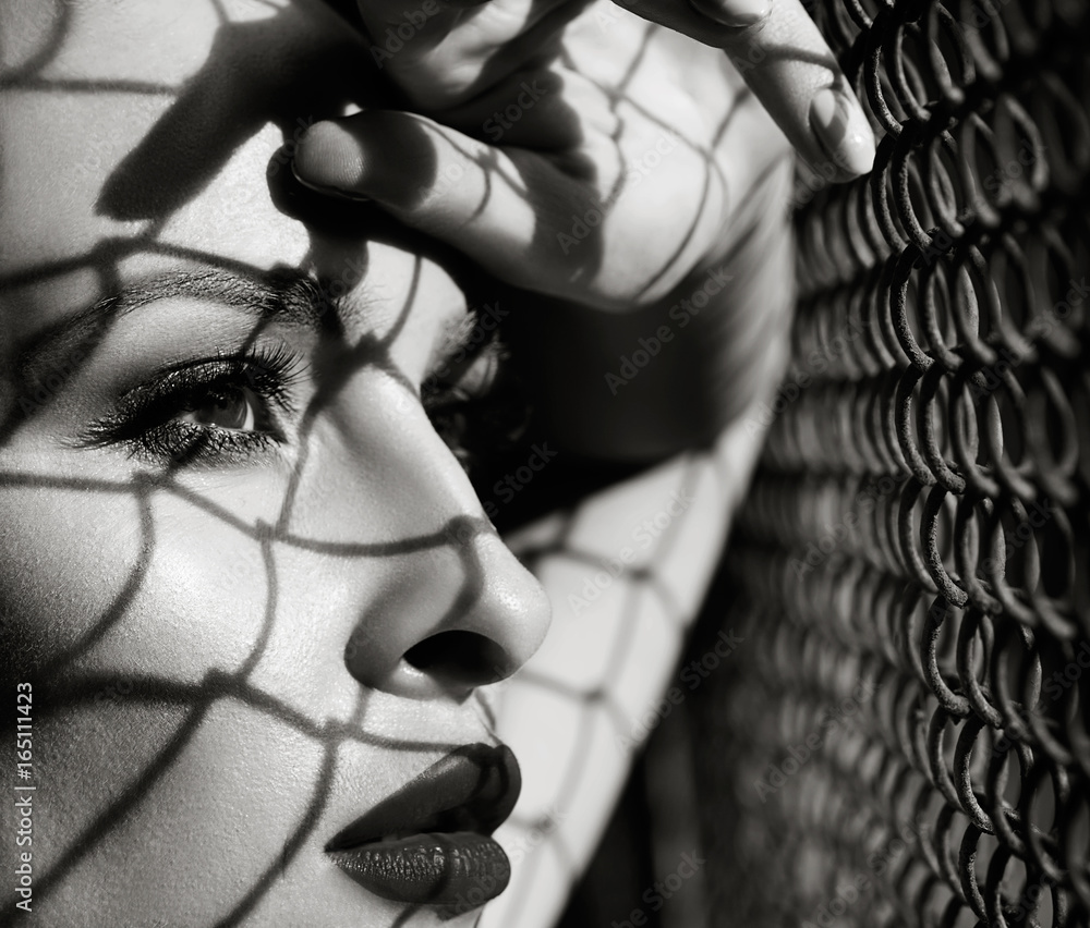 close up fashion woman model portrait black and white, shadows from grid on face. close up fashion woman model portrait black and white, shadows from grid on face.