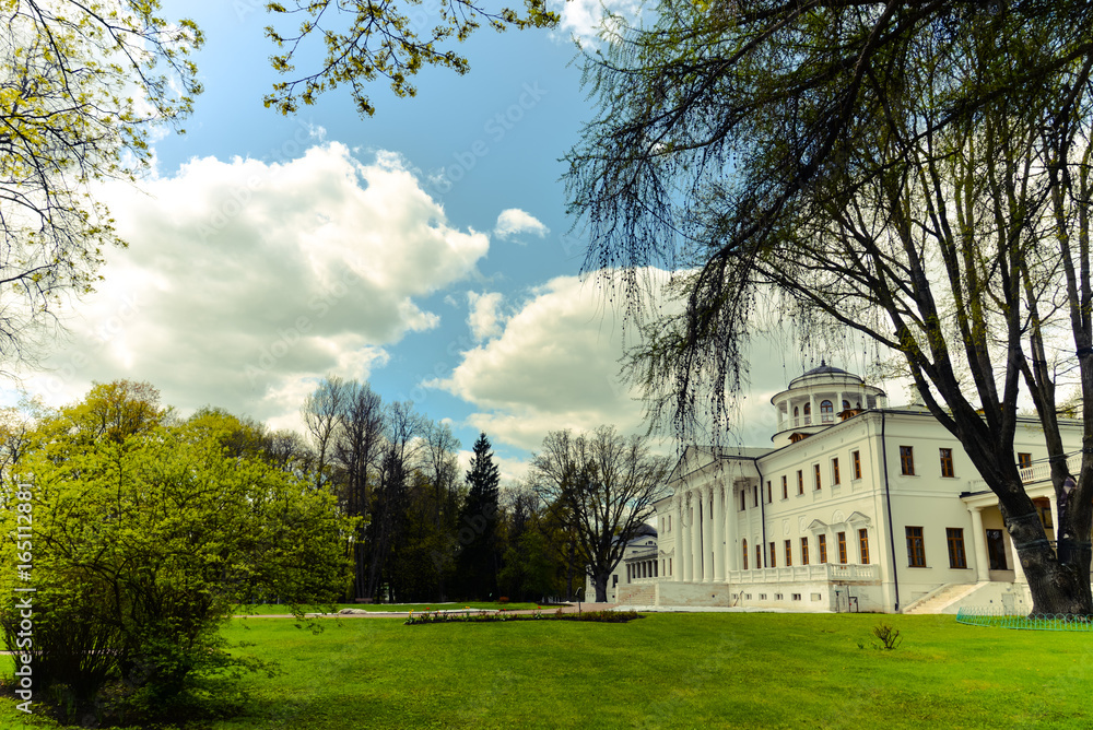 View on Ostafyevo palace in Moscow region and public park. Antique mansion 18-19 century in classicism style. Beautiful landscape with old manor, lawn, sky and trees for calendars, posters, prints.