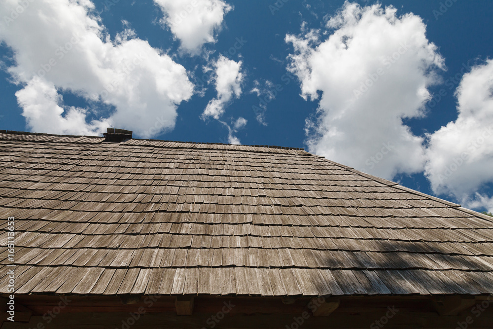 The roof is covered with wooden tiles against the blue sky. The roof is covered with wooden tiles against the blue sky.