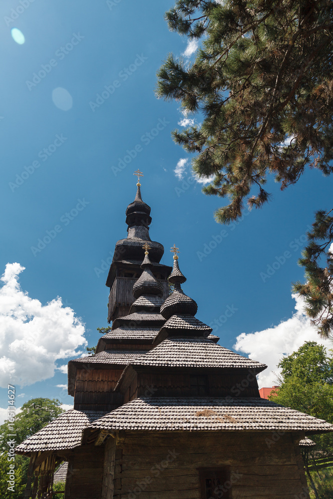 Old wooden Lemk church against a bright blue sky with clouds. Old wooden Lemk church against a bright blue sky with clouds.