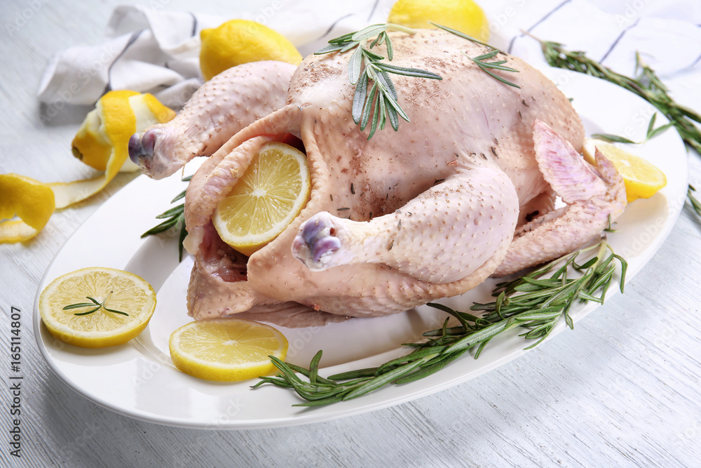 Composition with whole raw turkey, rosemary and lemons on wooden table Composition with whole raw turkey, rosemary and lemons on wooden table