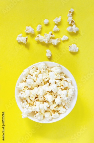 Movie theater popcorn in bowl on yellow retro background