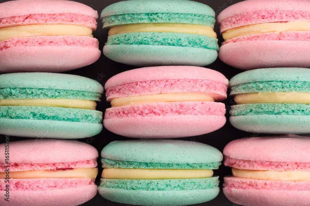 Fototapeta premium Top view of colorful macaroons on black background