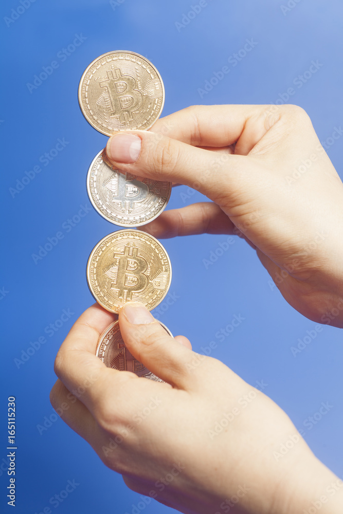 Four virtual coins bitcoins in hand on blue background Four virtual coins bitcoins in hand on blue background