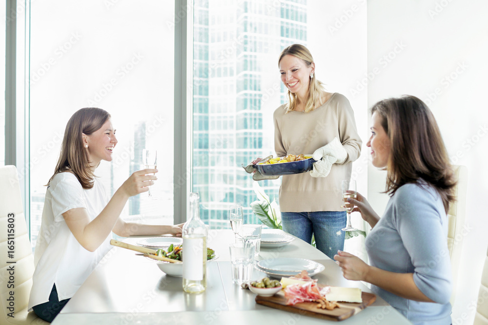 Happy young women dinning together while having party in the kitchen Happy young women dinning together while having party in the kitchen