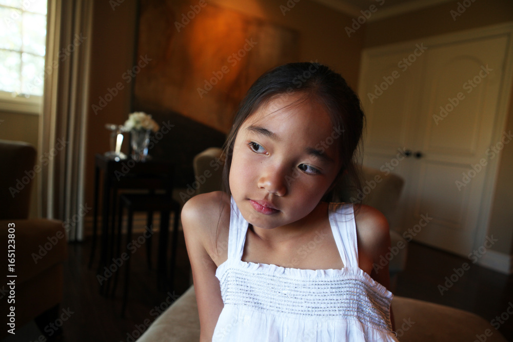 Asian girl sitting in bedroom showing wide angle view contemplative expression Asian girl sitting in bedroom showing wide angle view contemplative expression