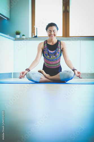 Young woman doing yoga at home in the lotus position. Yoga. Woman. Lifestyle