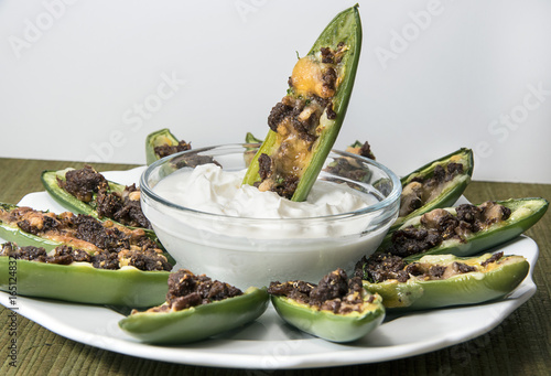 Stuffed jalapeno poppers with one dipping in sauce