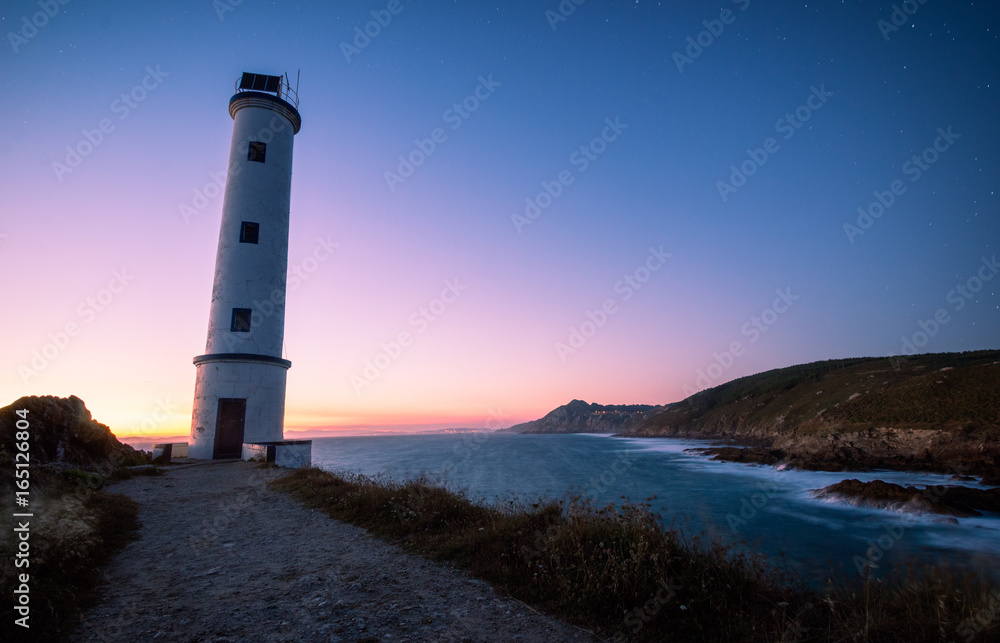Lighthouse at sunset in rocky coast in galicia, spain