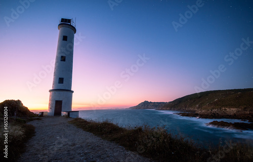 Lighthouse at sunset in rocky coast in galicia, spain