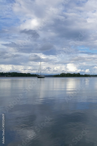 Lonely boat on calm sea and cloudy sky 