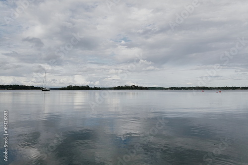 Solitaire boat on calm sea and cloudy sky 