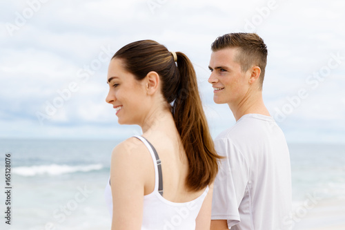 Young couple looking thoughtful while standing next to each other on beach