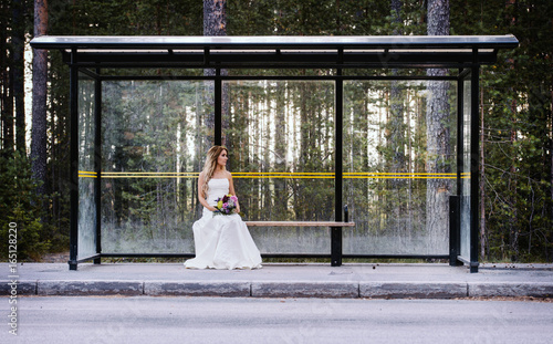 a lonely bride waiting on a bus stop photo