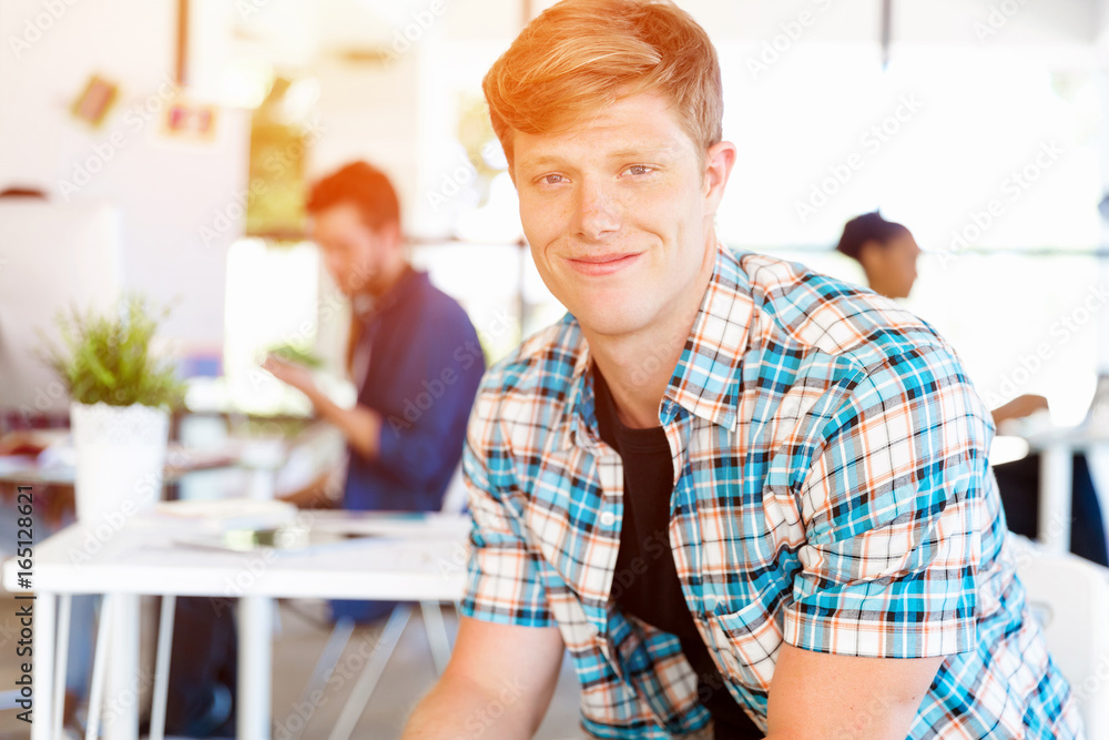 Young man sitting and looking at camera in office Young man sitting and looking at camera in office