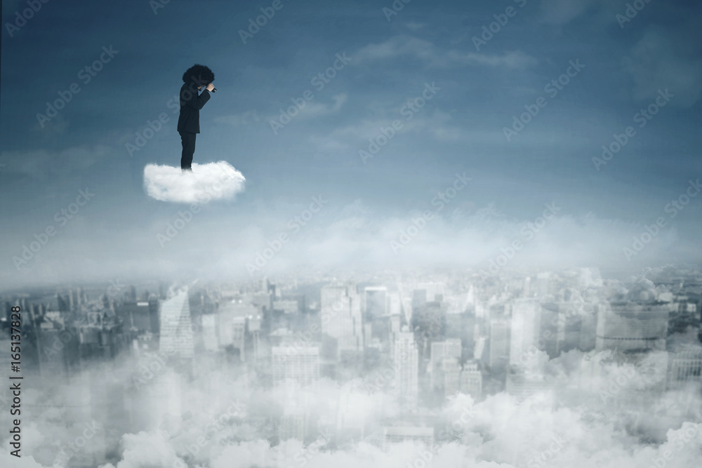 Afro businessman looking through binoculars