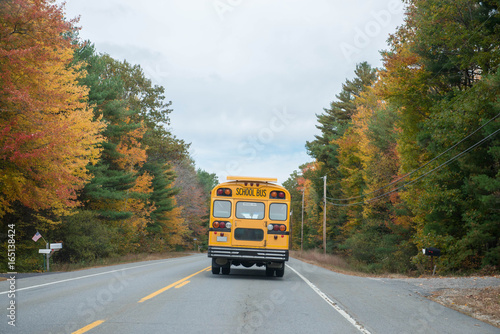 School bus drives down a country road in autumn