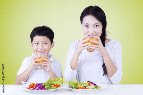 Boy with mother eat salad and drink juice