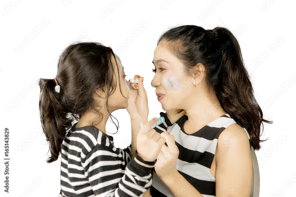 Mother painting a face of his daughter Mother painting a face of his daughter