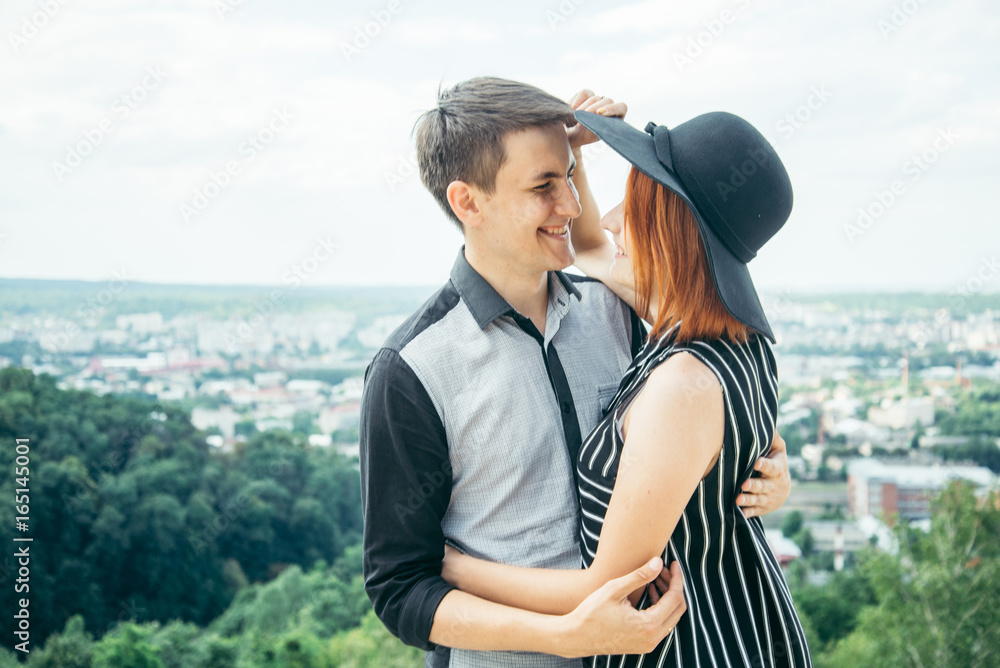 couple standing on the hill hugging and looking on city view