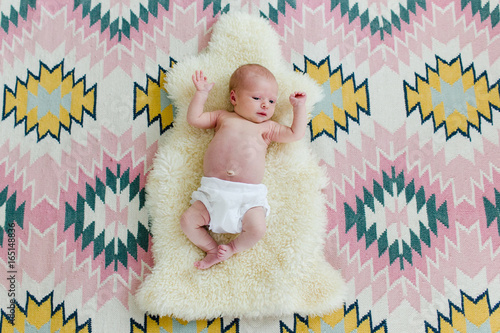 newborn laying on a sheepskin and a patterned rug