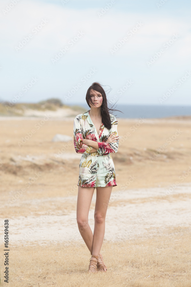 A beautiful woman standing in with arms crossed her hair blowing in the wind A beautiful woman standing in with arms crossed her hair blowing in the wind
