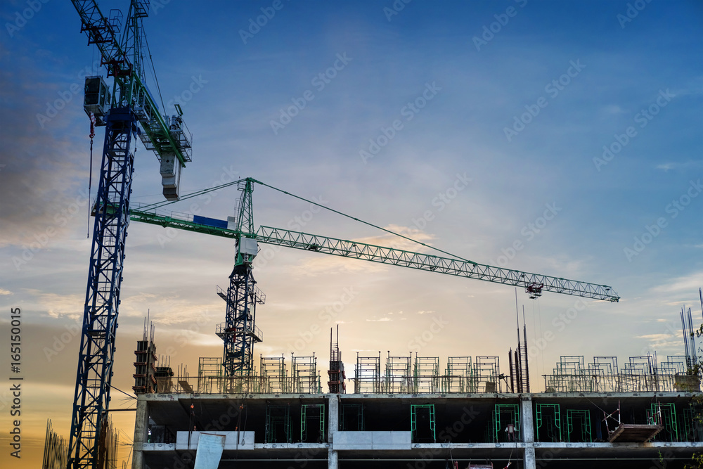 Under construction building with cranes in sunset