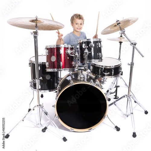 Canvas Print young caucasian boy plays drums in studio against white background