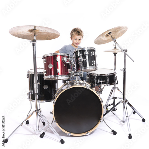 young caucasian boy plays drums in studio against white background