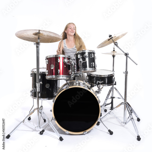 young blond teenage girl plays the drums in studio against white background