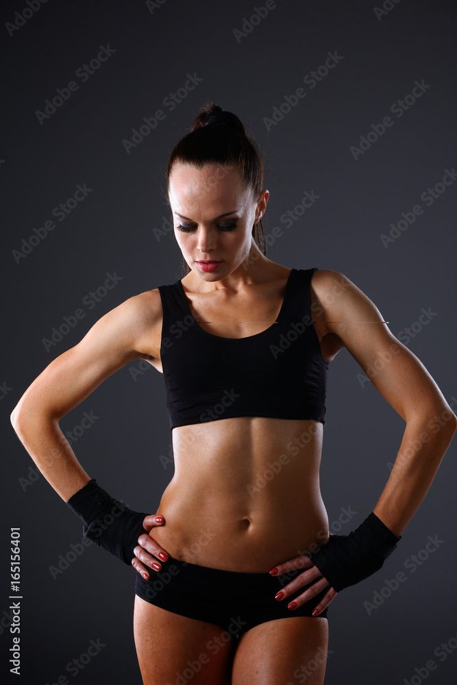 Muscular young woman standing on gray background Muscular young woman standing on gray background
