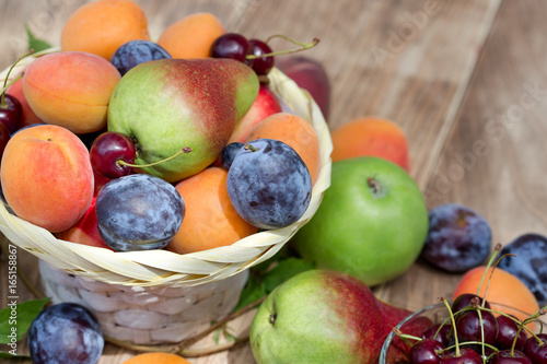 Eating healthy food - fresh organic fruits in wicker basket and on table