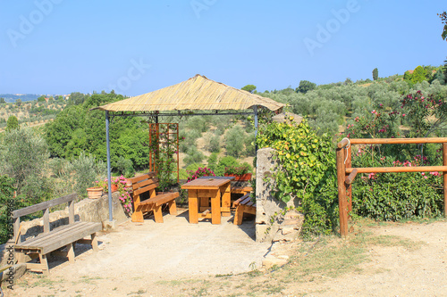 Wooden alcove with table and benches in summer. A place to rest in the heat in the mountains of the Tuscany region, Italy