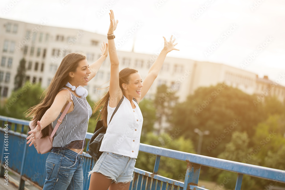 Two happy women are having fun together in the city in summer.