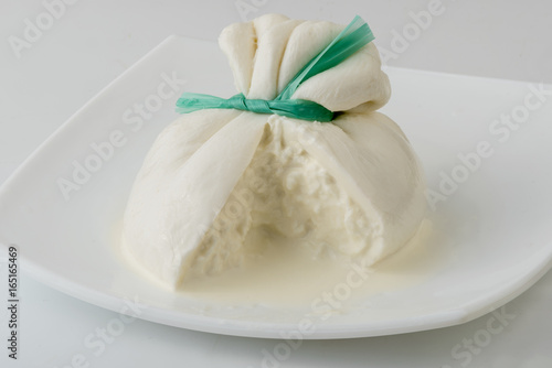 Burrata cheese isolated on white plate. Sliced fresh italian cheese made from mozzarella and cream.