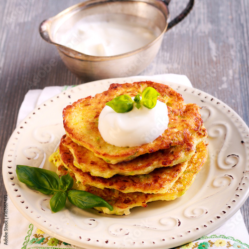 Zucchini and feta fritters with sour cream on plate