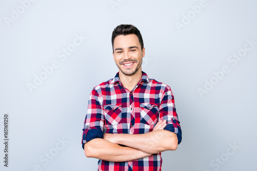 Success concept. Excited young stylish bearded brunet student in bright casual checkered shirt standing on light background