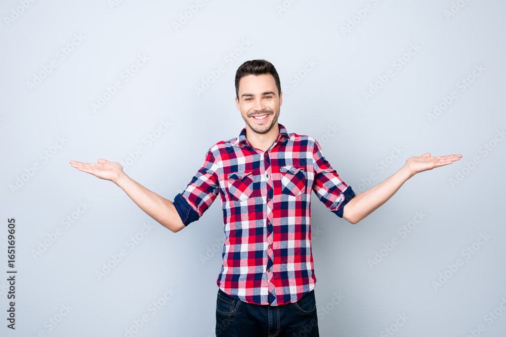 Cheerful brunet student in casual wear on pure background is gesturing with hands like he is holding something and need to choose between two options Cheerful brunet student in casual wear on pure background is gesturing with hands like he is holding something and need to choose between two options