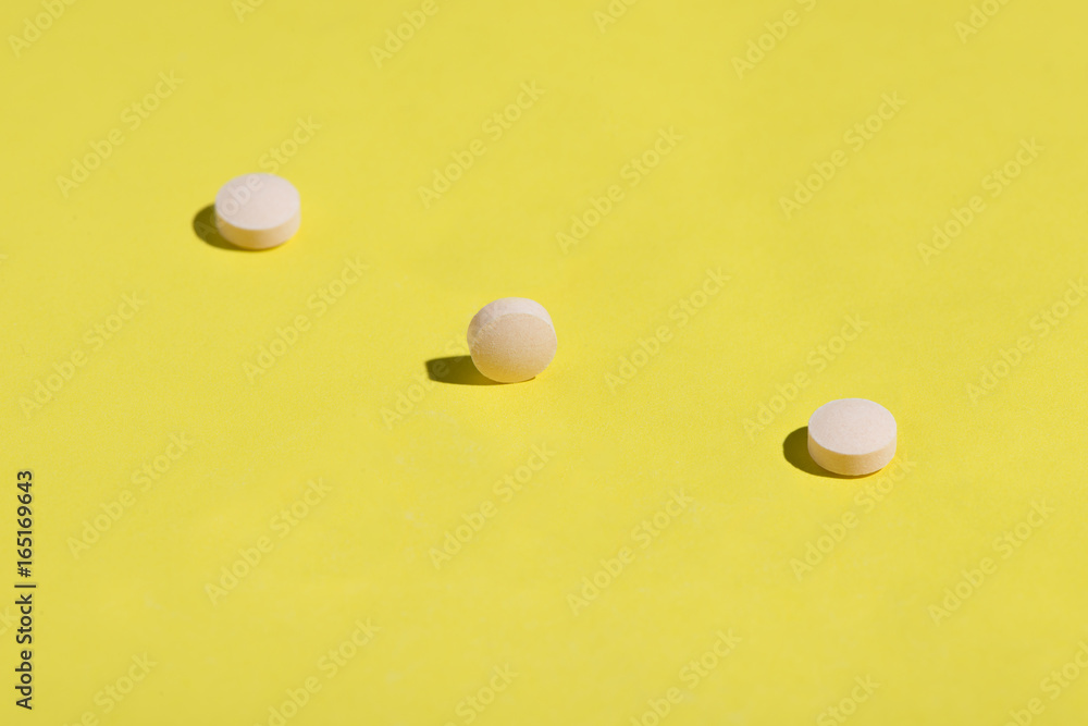 Little peach pills scattered on a bright yellow surface. Little peach pills scattered on a bright yellow surface.