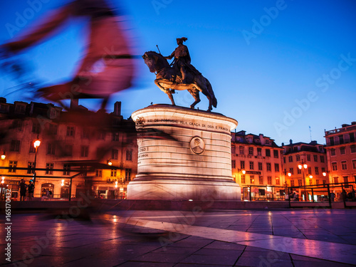  Figueira Square with the statue of King John I while a cyclist passing by. Lisbon, Portugal