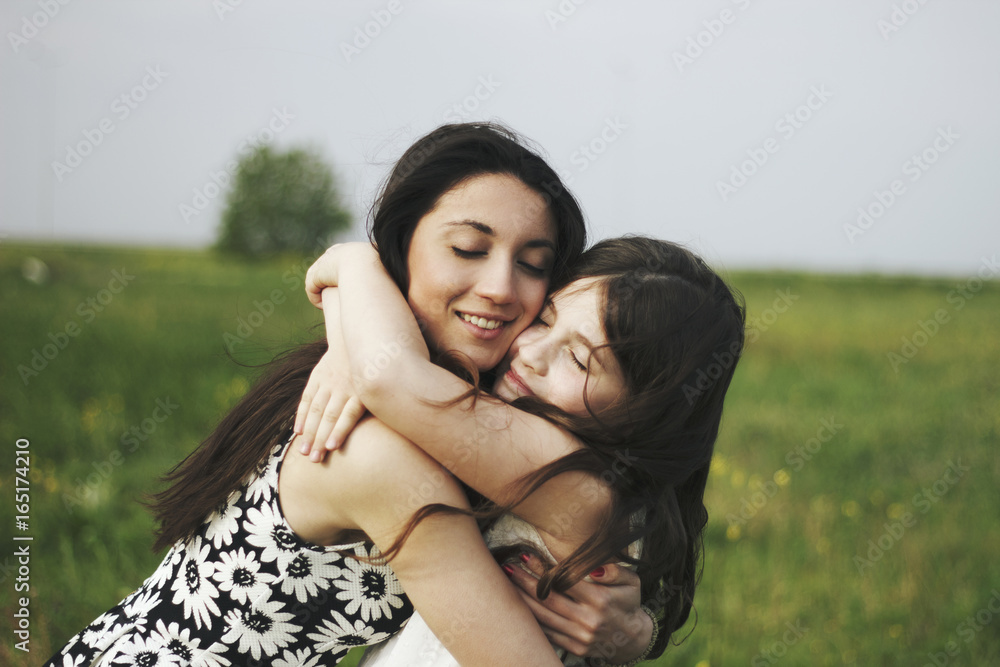 Happy sisters hugging together outdoors Happy sisters hugging together outdoors