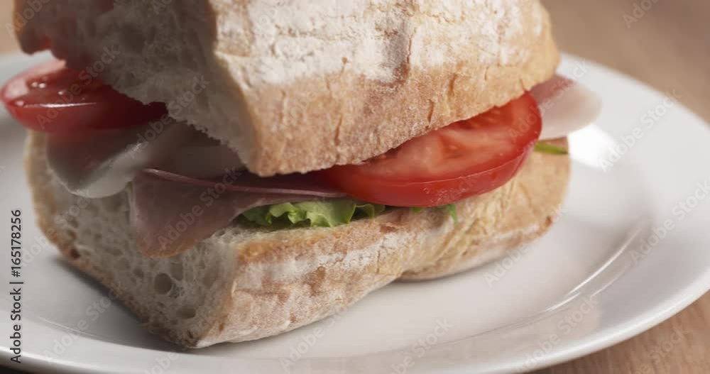 Slide shot of ciabatta sandwich with speck, mazzarella and vegetables Slide shot of ciabatta sandwich with speck, mazzarella and vegetables