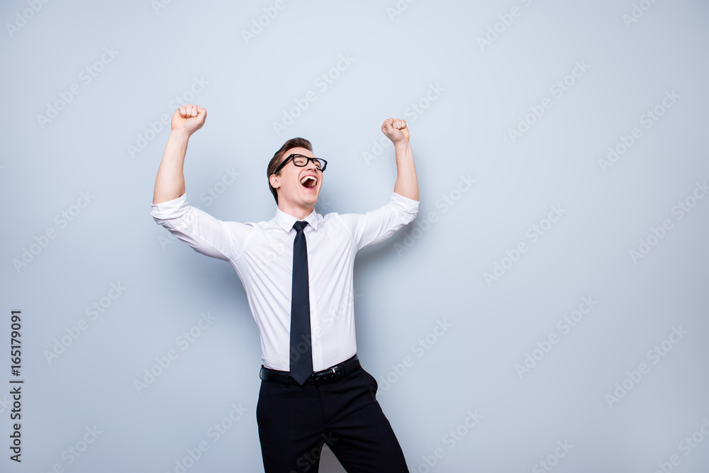 Yes! Successful young handsome student is celebrating. He is in a formal outfit and black stylish glasses, on pure background, with hands raised up Yes! Successful young handsome student is celebrating. He is in a formal outfit and black stylish glasses, on pure background, with hands raised up