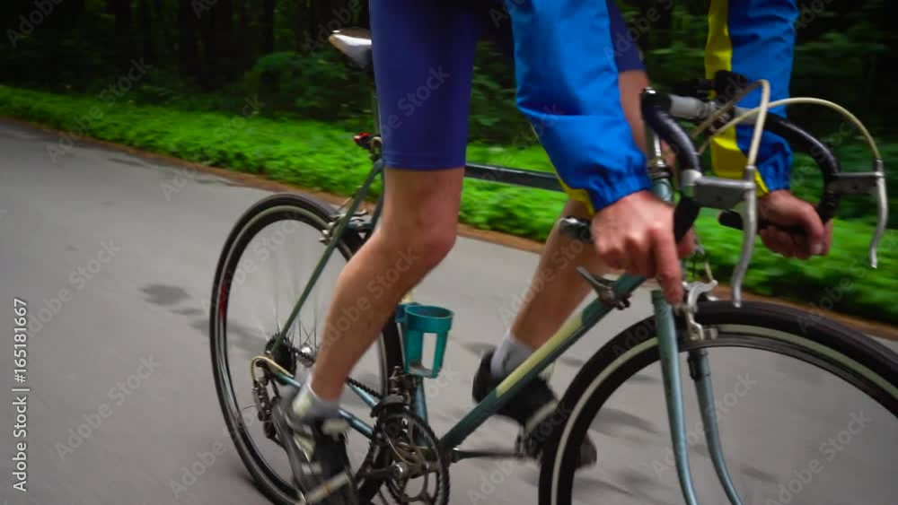 Middle-aged man is riding a road bike along a forest road Middle-aged man is riding a road bike along a forest road